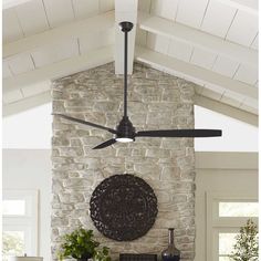 a living room with a stone fireplace and ceiling fan