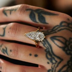 a close up of a person's hand holding a ring with a diamond on it