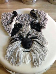 a cake decorated with a dog's face on top of a white frosted plate