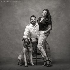 a man and woman pose for a black and white photo with a dog on a stool