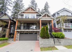 a large house with lots of trees and bushes in front of the garage door, on a cloudy day