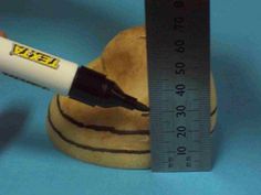 a hand holding a white marker next to a brown doughnut on a blue surface