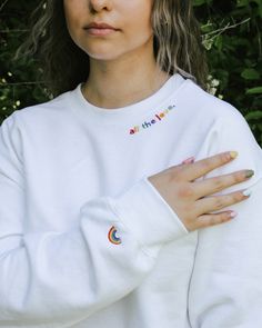 a woman with long hair wearing a white sweatshirt and holding her hands on her chest