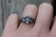 a close up of a person's hand holding an engagement ring with two stones