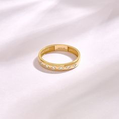 a gold ring with three small diamonds on the inside and outside, sitting on a white sheet