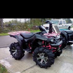 a black and red four - wheeler parked in front of a truck on the street