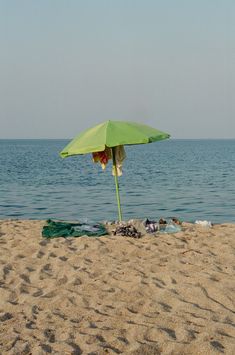 an umbrella is on the beach next to trash