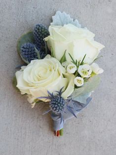 a bridal bouquet with white roses and blue thistles on the side by itself