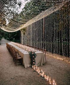 a long table is set up with candles and greenery for an outdoor wedding reception