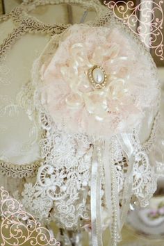 a white lace doily with a pink flower on it and pearls in the center