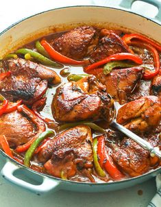 a pan filled with meat and peppers on top of a table