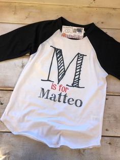 This listing includes one UNISEX 3/4 sleeve raglan baseball tee OR standard white short sleeve tee in youth or toddler. Scribble Letter With Your Little One's Name.. PLEASE include the name and letter as you wish it to be printed into order notes.. We absolutely love this brand of tee's... They will not shrink and hold up great for daily wear. The material is incredibly soft and the design is dyed into the fabric. No more peeling or cracking like vinyl or screen printing. Our process allows the White Cotton Baseball Jersey For Baseball Season, White Baseball Collar Top With Team Name, White Cotton Baseball Jersey, White Cotton Tops With Baseball Collar, White T-shirt With Baseball Collar And Pre-shrunk, White Baseball Collar T-shirt With Letter Print, White T-shirt With Letter Print And Baseball Collar, White Long Sleeve T-shirt With Lettering, White Tops With Graphic Print And Baseball Collar