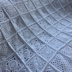 a white crocheted blanket on top of a bed