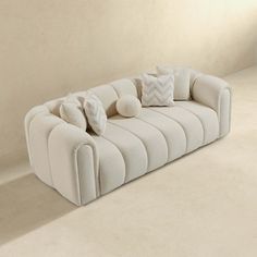 a white couch with several pillows on it in a room that is clean and ready for someone to use