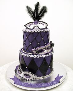 a three tiered cake decorated in purple and black with a feather on the top