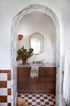 a bathroom with a sink, mirror and checkered tile flooring in the room