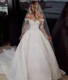 a woman in a white wedding dress standing next to a window