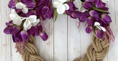 purple and white flowers are tied to a rope wreath