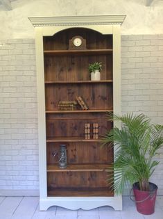 a wooden bookcase with plants and books on it