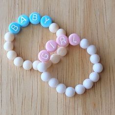 two bracelets made out of candy beads with the word baby spelled in pink, blue and white