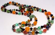 "Long Strand Necklace of Multi Color Glass Beads and Matching Clip Earrings. Glass Bead Colors Are: Orange, Green, Black, White, Gold and Blue Iridescent. Each Color Bead is a Different Shape and Type Such as : Orange-Barrel-Crackel, Green-Oval- Molded Cats Eye, White-Round-Clear, Blue Iridescent Carnival-Round, Gold-Faceted-Round, Etc. Necklace is 50\" Long and Can be Worn Long or Doubled or Tripled. Earrings Are 1\" in diameter and Stamped Made in West Germany. Colorful and Unusual! Necklace a Multicolor Czech Glass Jewelry For Party, Multicolor Czech Glass Party Jewelry, Costume Jewelry Glass Party Jewelry, Multicolor Beads For Party Costume Jewelry, Multicolor Beads For Costume Jewelry Party, Party Jewelry With Round Glass Beads, Unique Czech Glass Jewelry For Party, Multicolor Costume Jewelry Beads For Party, Orange Round Beads Jewelry For Party