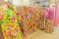 there is a woman that is looking at some fabrics on display in the store window