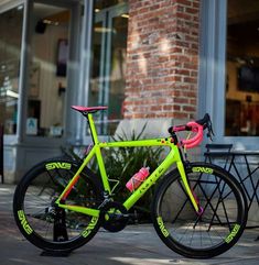 a neon green bike parked on the side of a street next to a brick building