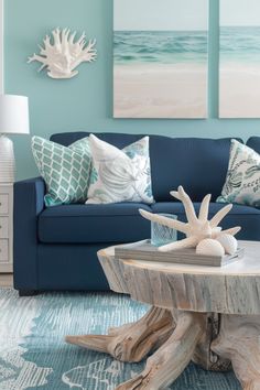 a living room with blue couches and sea shells on the coffee table in front of it