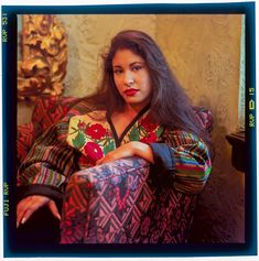 a woman sitting in a chair with her arms crossed and looking off to the side