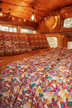 a bed in a room with lots of pillows and blankets on top of the bedspread