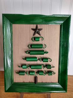 a christmas tree made out of green coils in a frame with a star on top