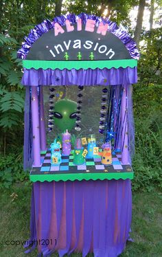 an alien themed birthday party with purple and green decorations on the table, in front of some trees