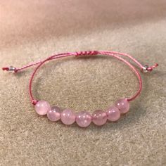 These soft pink rose quartz bracelets are fashionable and healing! Rugged and durable for 24/7 wear, but, still dainty, natural and feminine for her, this rose quartz bracelet is perfect for the whole family, gift giving. party favors, wedding parties and even for a gender reveal! This genuine gemstone bracelet features seven round 6mm rose quartz beads in the center of a comfy knotted bracelet. This trendy string bracelet is strung on durable high quality heavy braided nylon cord with a sliding Adjustable Rose Quartz Beaded Bracelets For Friendship, Pink Natural Stones Bracelet For Friendship, Casual Rose Gold Bracelets As Gift, Casual Rose Gold Bracelet Perfect For Gifts, Casual Rose Gold Bracelet For Gift, Casual Rose Gold Bracelet Gift, Adjustable Rose Quartz Beaded Bracelet With Round Beads, Pink Round Beads Braided Casual Bracelets, Casual Pink Braided Bracelets With Round Beads