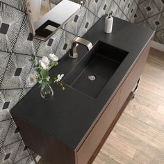 a bathroom sink sitting on top of a counter next to a vase with flowers in it