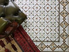 a green leather chair sitting on top of a rug next to a wall covered in tiles