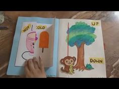 a child's hand is holding an open book with pictures of animals and trees