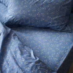 a bed covered in blue sheets and pillow cases with flowers printed on the coverlet