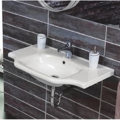 a bathroom sink sitting under a mirror next to a toilet paper dispenser