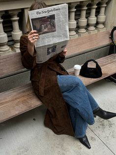 a person sitting on a bench reading a newspaper