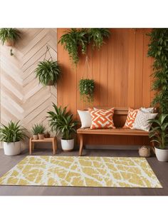 a wooden bench sitting next to plants on top of a hard wood floor covered in white and orange pillows