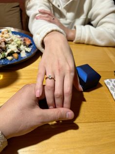 two people sitting at a table with food on the table and one person holding their hand