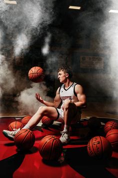 a basketball player sitting on the floor with his feet up and balls in front of him