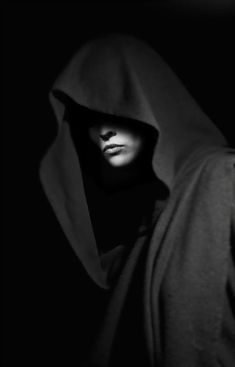 a person wearing a hooded jacket in the dark with their head covered by a hood