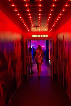 a woman walking down a hallway with red lights