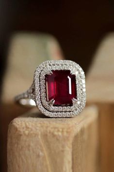 a close up of a ring with a red stone in the middle and white diamonds around it