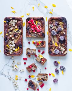 three desserts with berries, nuts and other toppings on a white table top