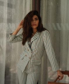 a woman standing in front of a curtain wearing a striped suit and matching heels with her hands on her hips