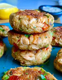 several crab cakes stacked on top of each other in front of lemons and ketchup