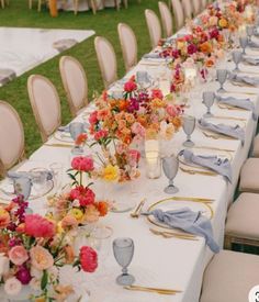 a long table is set with white linens and floral centerpieces on it