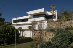 a large white house sitting on top of a lush green hillside next to a stone wall